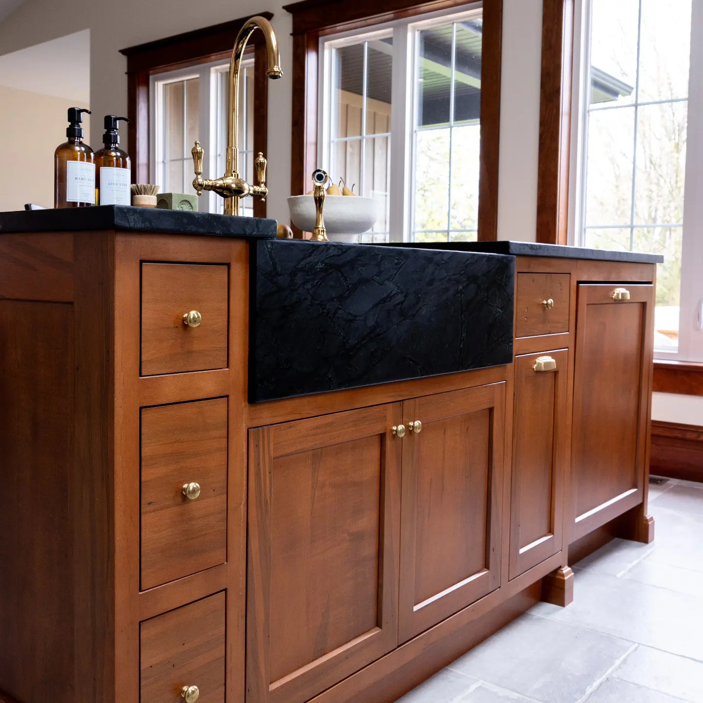 Stained maple kitchen with island and hidden appliance cabinetry by Heirlooms Custom Cabinetry