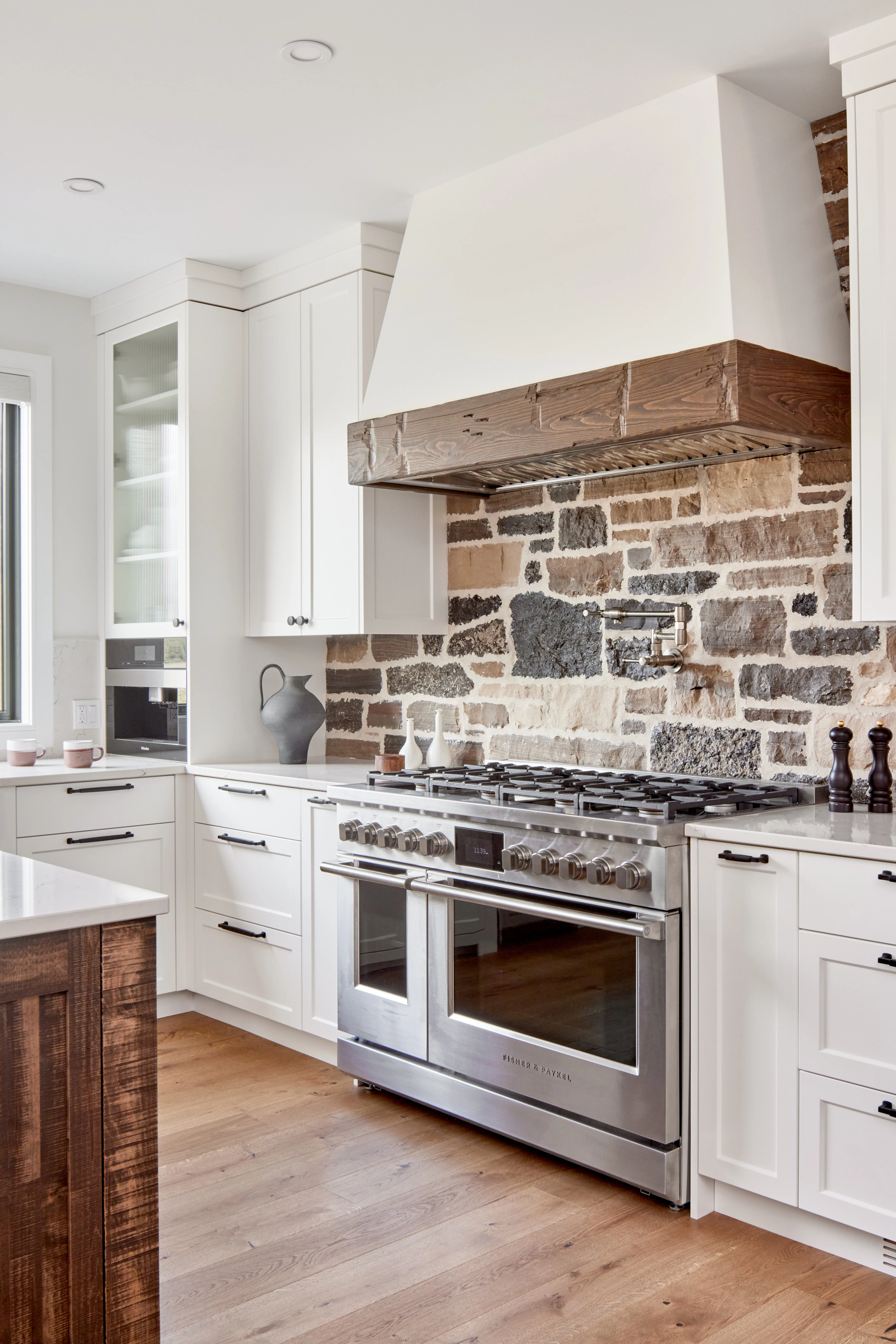 Custom kitchen with stone backsplash and professional range by Heirlooms