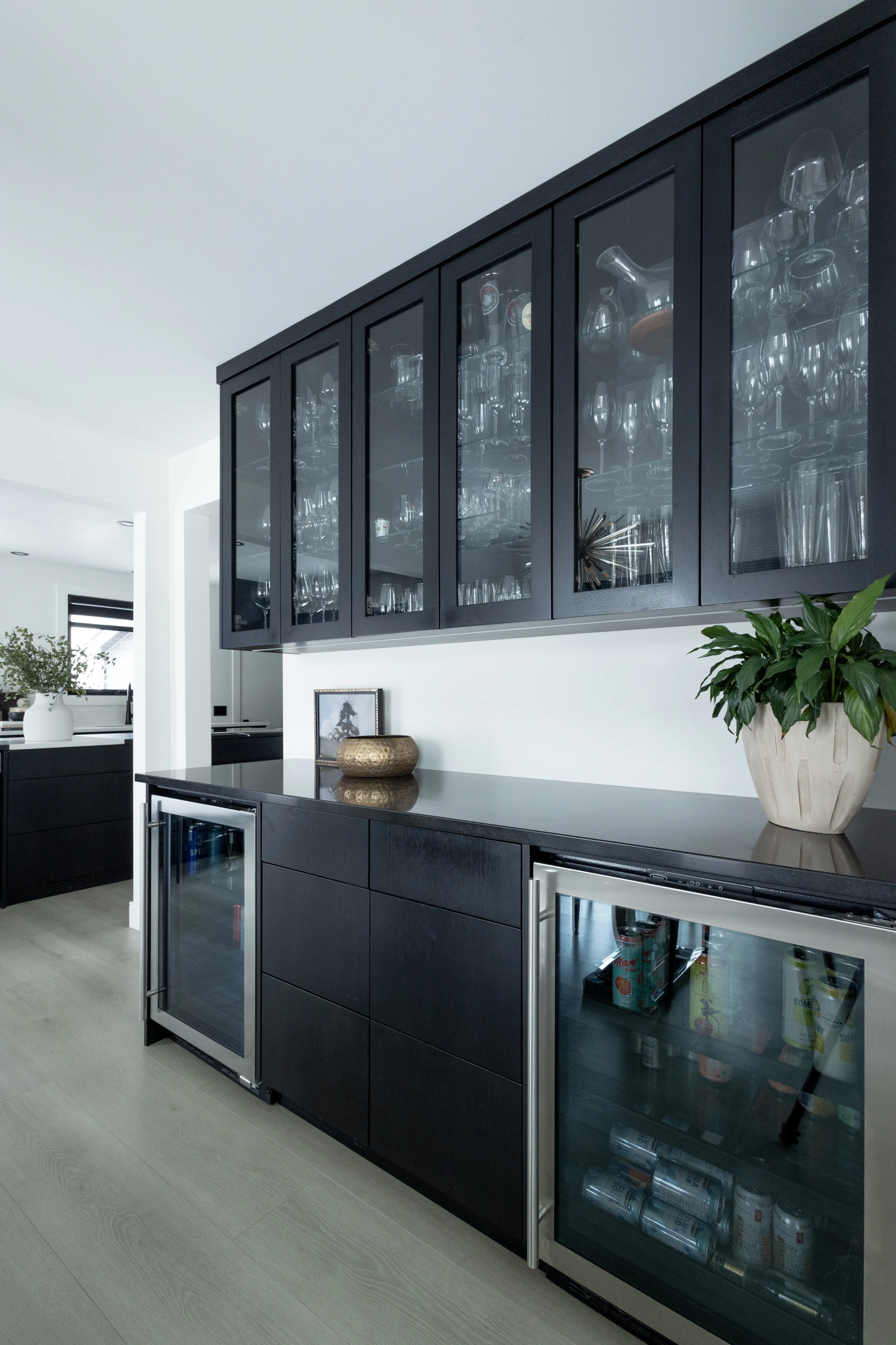 Custom black bar with glass-front cabinets and wine coolers by Heirlooms