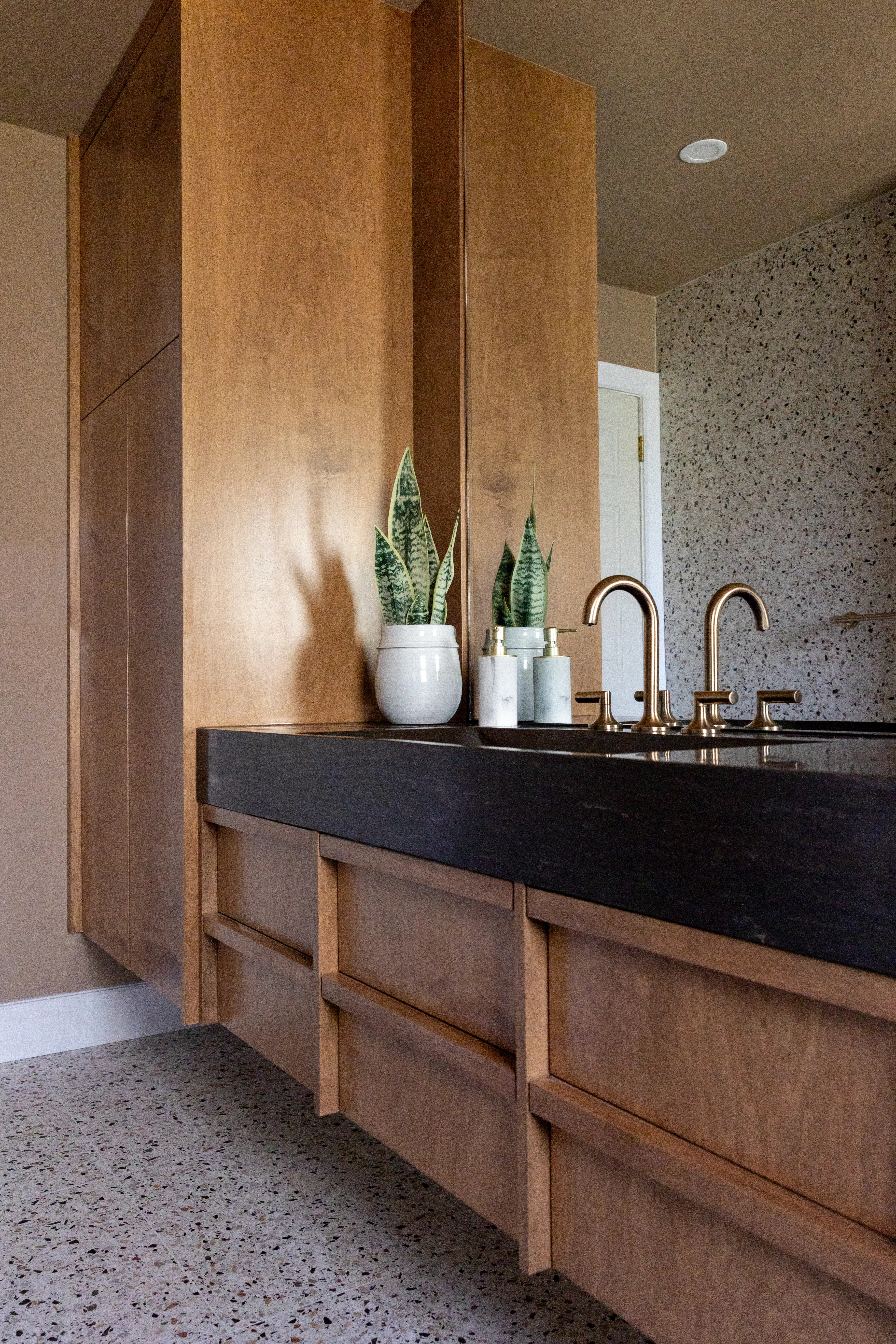 Custom warm wood bathroom vanity with brass fixtures by Heirlooms